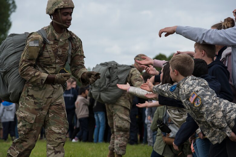 A U.S. static-line paratrooper gives his military service patches to the eager hands of French boys and girls outside of Sainte-Mère-Église, France, June 9, 2019. The military service patch, a unique design embodying the unit it represents, is a highly coveted souvenir for children in Normandy during D-Day commemorations. (U.S. Air Force photo by Senior Airman Kristof J. Rixmann)