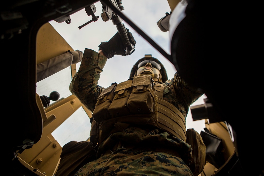 A Marine sits inside of a military vehicle.