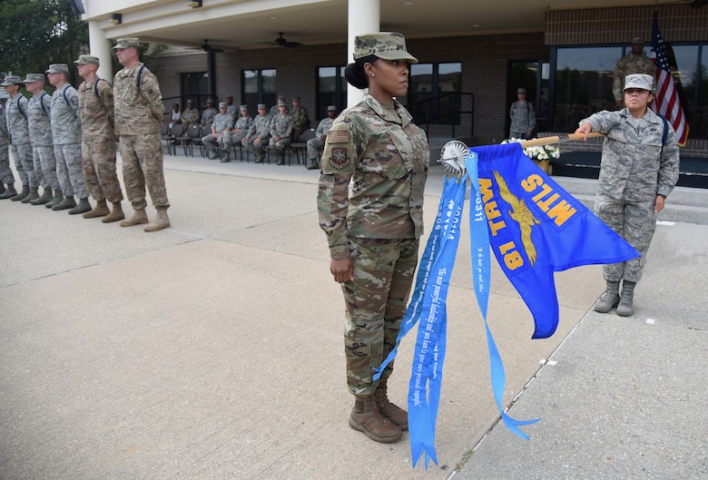 U.S. Air Force Master Sgt. Ladwidia Castro, 81st Training Support Squadron military training leader course student, adds a ribbon to a streamer to the 81st Training Wing Military Training Leadership schoolhouse flag during a MTL course graduation ceremony at the Levitow Training Support Facility on Keesler Air Force Base, Mississippi, May 30, 2019. The MTL course is responsible for training approximately 120 MTLs per year. Those MTLs are then responsible for training approximately 30,000 Airmen in 49 different locations that fall under Air Education and Training Command. (U.S. Air Force photo by Kemberly Groue)