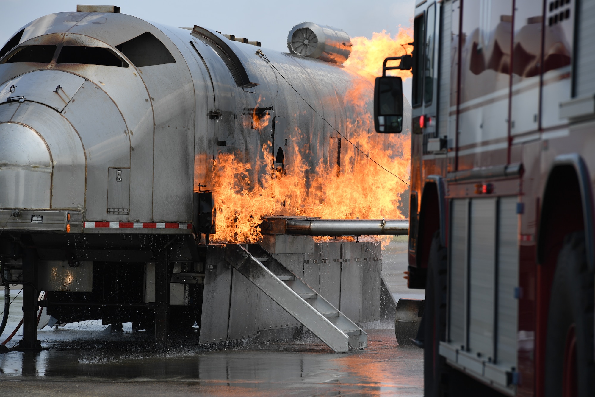 A Keesler fire truck is used to extinguish a fire on a mock C-123 training device during an aircraft rescue fire fighting training on Keesler Air Force Base, Mississippi, June 4, 2019. The joint agency training allowed the Keesler Fire Department, Gulfport Combat Readiness Training Center Fire Department, Stennis Airport Fire Department and the U.S. Naval Air Station Pensacola Gulf Coast Fire Rescue to meet the semi-annual training requirement to practice aircraft rescue and live fire training evolutions. (U.S. Air Force photo by Kemberly Groue)