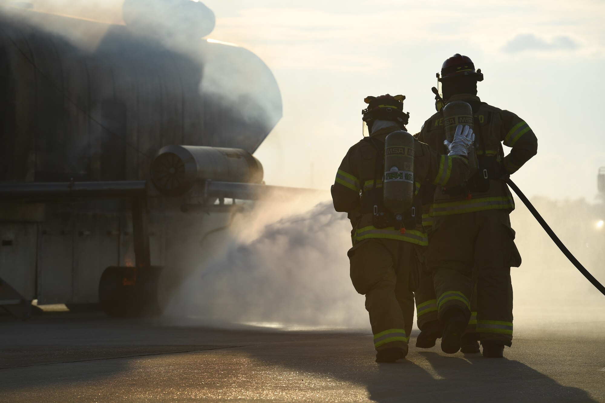Keesler firefighters use a hand-held hose to extinguish a fire on a mock C-123 training device during an aircraft rescue fire fighting training on Keesler Air Force Base, Mississippi, June 4, 2019. The joint agency training allowed the Keesler Fire Department, Gulfport Combat Readiness Training Center Fire Department, Stennis Airport Fire Department and the U.S. Naval Air Station Pensacola Gulf Coast Fire Rescue to meet the semi-annual training requirement to practice aircraft rescue and live fire training evolutions. (U.S. Air Force photo by Kemberly Groue)