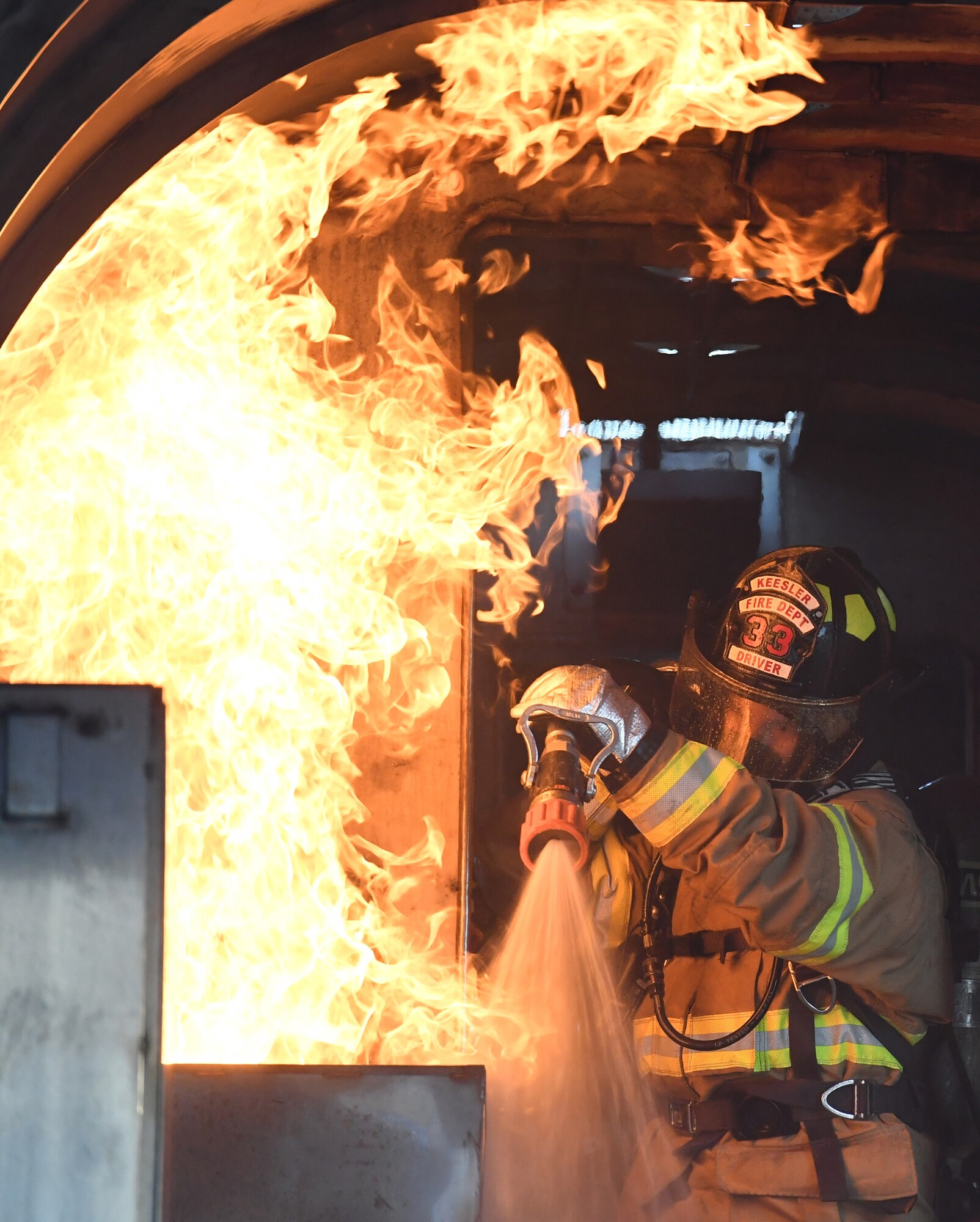 A Keesler firefighter uses a hand-held hose to extinguish a fire inside a mock C-123 training device during an aircraft rescue fire fighting training on Keesler Air Force Base, Mississippi, June 4, 2019. The joint agency training allowed the Keesler Fire Department, Gulfport Combat Readiness Training Center Fire Department, Stennis Airport Fire Department and the U.S. Naval Air Station Pensacola Gulf Coast Fire Rescue to meet the semi-annual training requirement to practice aircraft rescue and live fire training evolutions. (U.S. Air Force photo by Kemberly Groue)