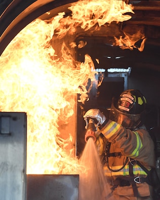 A Keesler firefighter uses a hand-held hose to extinguish a fire inside a mock C-123 training device during an aircraft rescue fire fighting training on Keesler Air Force Base, Mississippi, June 4, 2019. The joint agency training allowed the Keesler Fire Department, Gulfport Combat Readiness Training Center Fire Department, Stennis Airport Fire Department and the U.S. Naval Air Station Pensacola Gulf Coast Fire Rescue to meet the semi-annual training requirement to practice aircraft rescue and live fire training evolutions. (U.S. Air Force photo by Kemberly Groue)