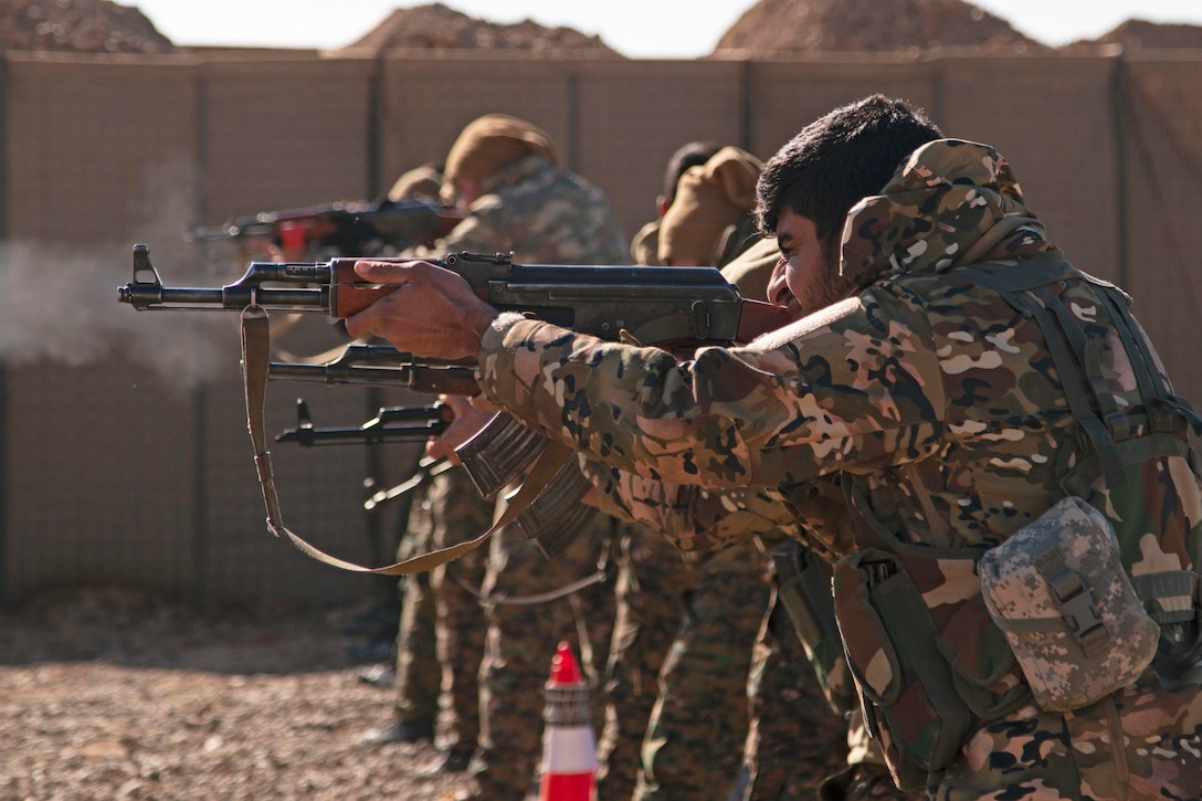 Syrian fighters fire rifles at a range.