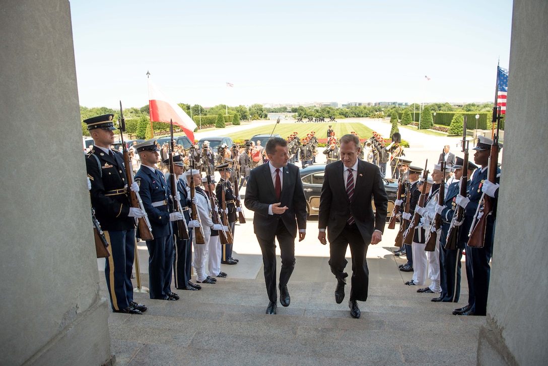Acting Defense Secretary Patrick M. Shanahan walks up the Pentagon steps while listening to another leader.
