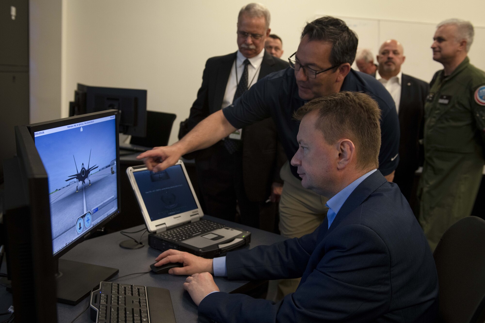 A man sits before a computer screen that is running aircraft simulation software.