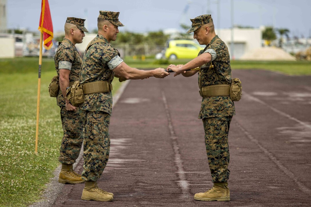 U.S. Marine Corps Col. Joon H. Um, left, ceremoniously passed the noncommissioned officer sword to Sgt. Maj. John R. Preston, right, during a relief and appointment ceremony May 31, 2019, at Camp Kinser, Okinawa, Japan. Sgt. Maj. Kenneth A. Miller ceremoniously transferred accountability and authority of enlisted Marines to Sgt. Maj. John R. Preston during the ceremony. Um, the commanding officer of Combat Logistics Regiment 35, 3rd Marine Logistics Group, is a native of Tampa, Florida. Miller, the outgoing regimental sergeant major of CLR-35, 3rd MLG, is a native of Woodland, California. (U.S. Marine Corps photo by Lance Cpl. Terry Wong)