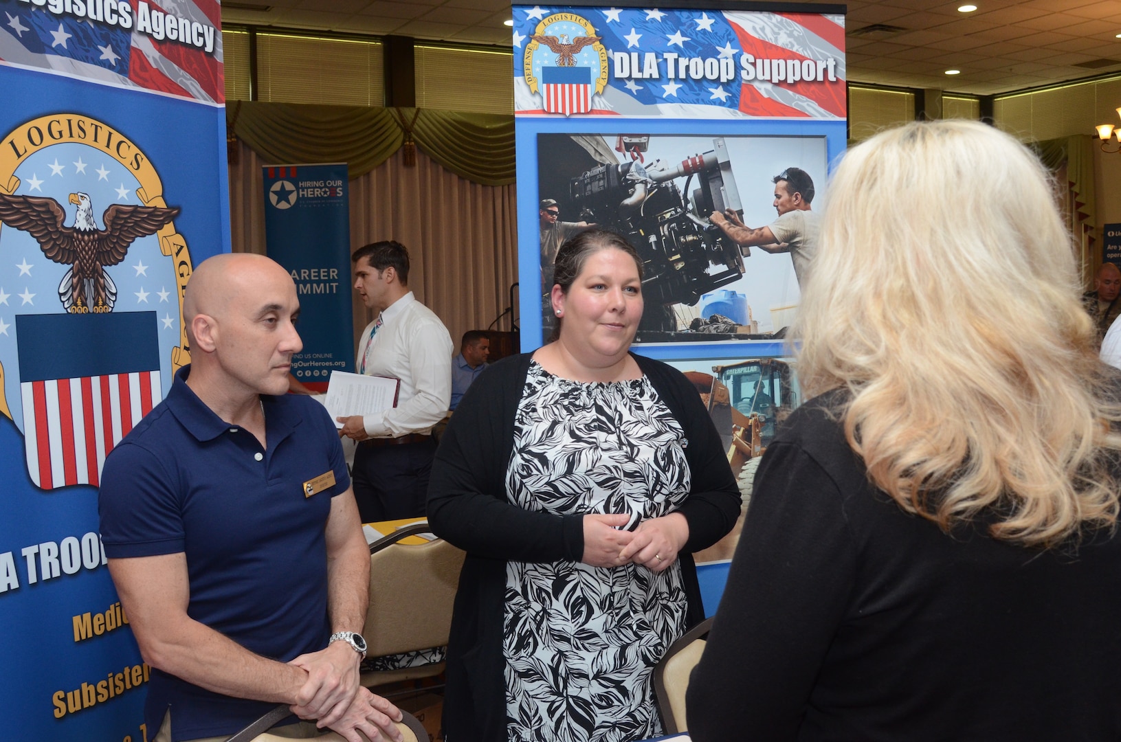 Jose Pereira, DLA Troop Support Industrial Hardware tech/quality division chief, left, and Annie Firth, Troop Support lead human resources specialist, right of Pereira, speak with a potential applicant at Joint Base McGuire-Dix-Lakehurst, New Jersey, May 30, 2019.