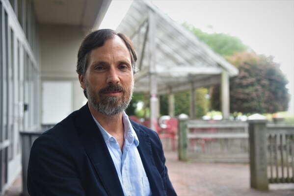 Man with beard in suit jacket sits outside posing for a portrait photo