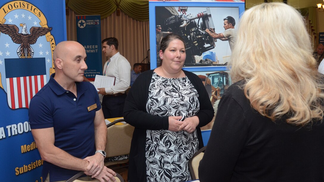 Jose Pereira, DLA Troop Support Industrial Hardware tech/quality division chief, left, and Annie Firth, Troop Support lead human resources specialist, right of Pereira, speak with a potential applicant at Joint Base McGuire-Dix-Lakehurst, New Jersey, May 30, 2019.