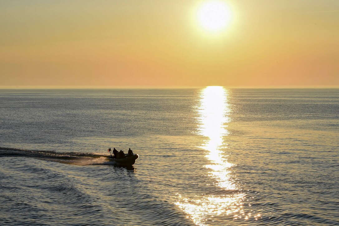 Sailors travel through waters in a small boat.