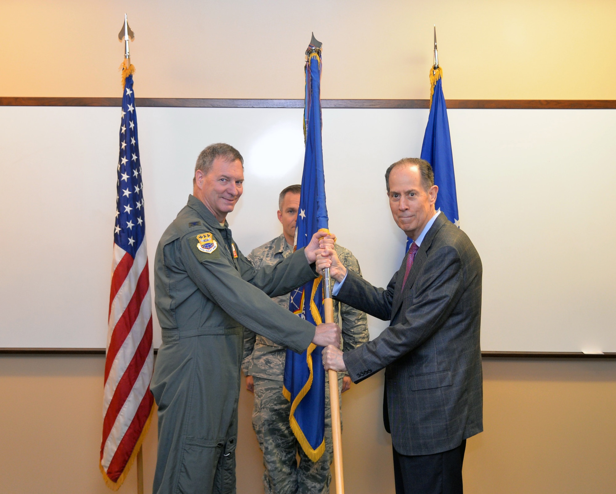 Col. Terry W. McClain, 433rd Airlift Wing commander, hands the wing guidon to Wayne I. Fagan, The Dee Howard Foundation chair, as Fagan is inducted into the Alamo Wing's Honorary Commander Program during a ceremony June 12, 2019 at Joint Base San Antonio-Lackland, Texas.