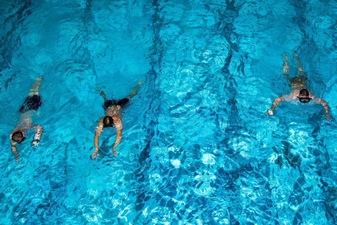 Three sailors swimming in a pool.