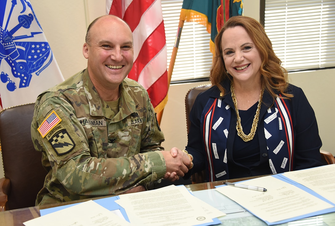 DLIFLC Commandant, Col. Gary Hausman and NSA NCS Commandant Diane M. Janosek shake hands after signing an agreement that enables U.S. service members to apply NCS completed coursework toward an Associate of Arts in Foreign Language degree from DLIFLC.