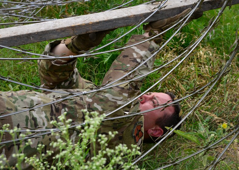 An Air Force recruiter with the 330th Recruiting Squadron navigates a barbed wire roadblock following instruction from Survival, Evasion, Resistance and Escape (SERE) cadre members from the 66th Training Squadron, Det. 3, at Joint Base San Antonio-Lackland June 3, 2019. Survival, Evasion, Resistance and Escape (SERE) cadre from are responsible for both the four-day Evasion and Conduct After Capture Course and the 15-day SERE Specialist Training Orientation Course at Joint Base San Antonio-Lackland. ECAC was the first stop for recruiters from the 330th RCS who travelled from across the United States to attend this biannual squadron training intended to immerse recruiters into SERE training in order for them to be better able to recruit Air Force SERE candidates.