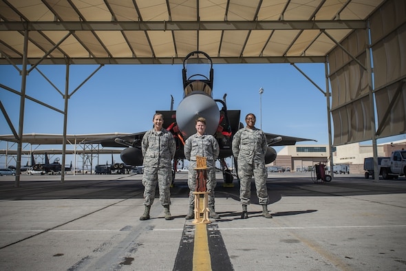 Three Air Force members standing in front of a plane.
