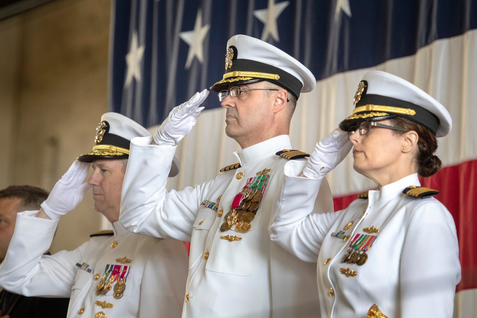 From left, Vice Adm. Thomas Moore, commander of Naval Sea Systems Command; Capt. Howard Markle, outgoing commander of Puget Sound Naval Shipyard & Intermediate Maintenance Facility; and Capt. Dianna Wolfson, incoming shipyard commander, salute the colors during the PSNS & IMF change of command ceremony June 12.