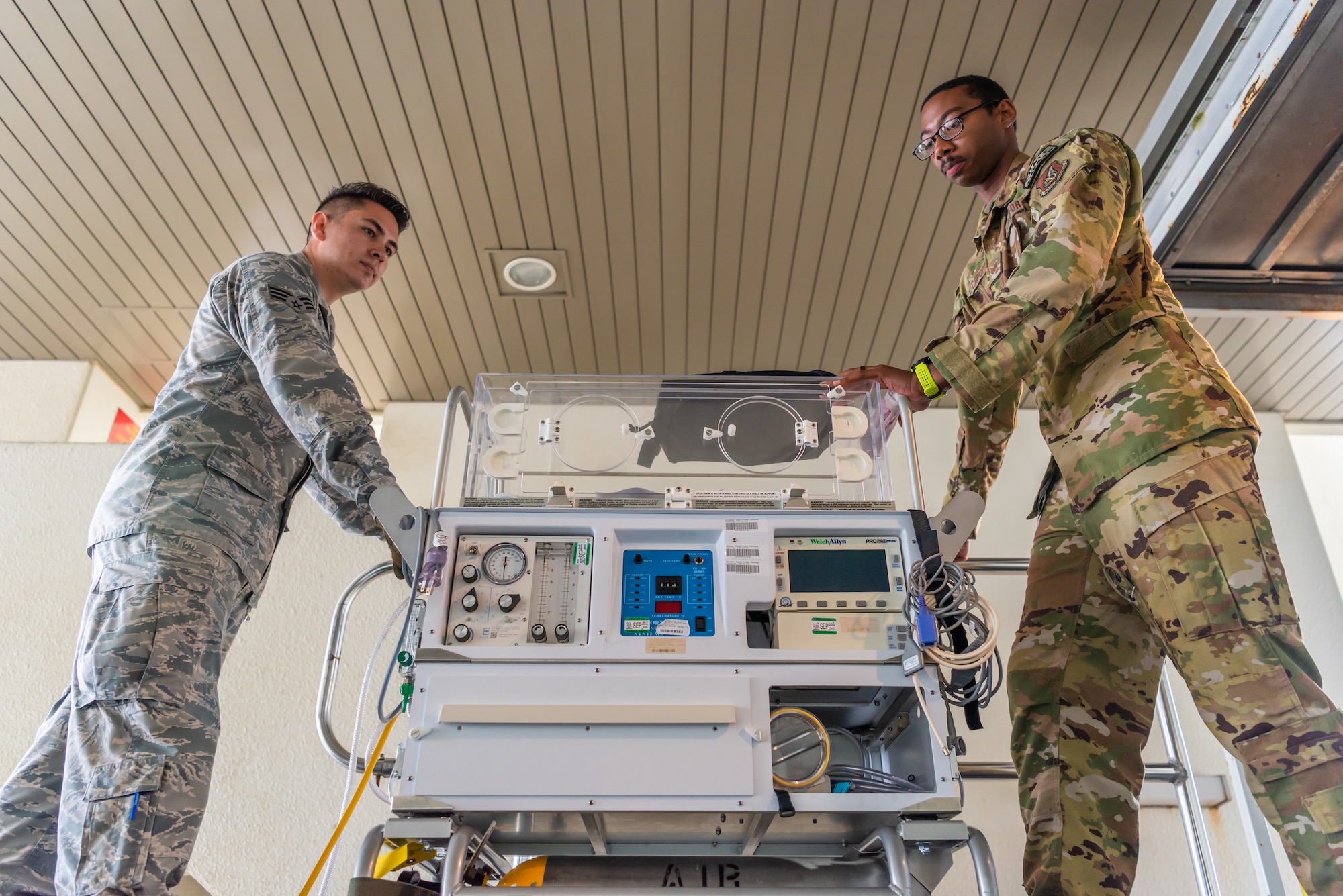 U.S. Air Force Staff Sgt. Derrik Pitchford, Critical Care Air Transport respiratory technician assigned to the 18th Aerospace Medicine Squadron, loads the neonatal transport system with Airman 1st Class Eliseo Rios, 18th AMDS aerospace medical technician, during a Neonatal Intensive Care Unit transportation course June 5, 2019, on Camp Foster, Japan. The 18th AMDS briefed the NICU nurses and technicians over the responsibilities of infant patient transportation on the ground, while the 18th AES focused on transportation while on the air. (U.S. Air Force photo by Airman 1st Class Cynthia Belío)