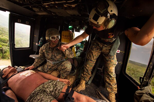 Sailors provide medical care to a mannequin on a helicopter.