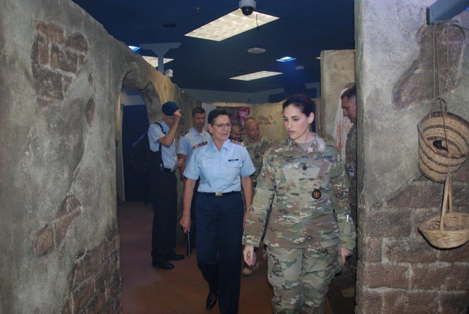 Lt. Col. Nadia Pearson (right), department chair, Combat Medic Training, Health Readiness Center of Excellence, guides Maj. Gen. Gesine Krüger (center), commander, German Bundeswehr Medical Academy, of combat medic simulated trauma scenario training during a visit to the Medical Education and Training Complex, on June 5, 2019. Krüger and a delegation of German medical professionals visited HRCoE to further strengthen the bonds and interoperability programs between our two nations.