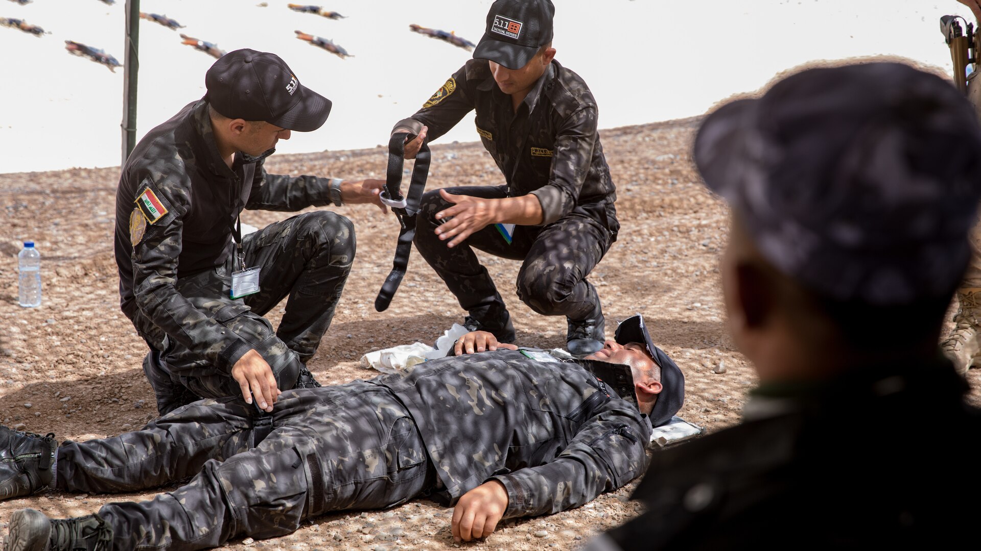 Iraqi provincial police members assigned to the 4th Ninawa Emergency Response Battalion prepare a tourniquet during a combat first aid class on Qayyarah West Airfield, Iraq, May 19, 2019. Iraqi students go through a four-week Wide Area Security Forces class taught by Canadian soldiers to learn essential combat skills like first aid, tactical movement, urban operations, and detainee procedures to enhance the Iraqi Security Forces’ combat skills and self-sufficiency. Coalition Forces are in Iraq at the invitation of the Government of Iraq to train and advise in support of the enduring mission to defeat Daesh. (Portions of this image were altered for operational security) (U.S. Army Reserve photo by Spc. DeAndre Pierce)