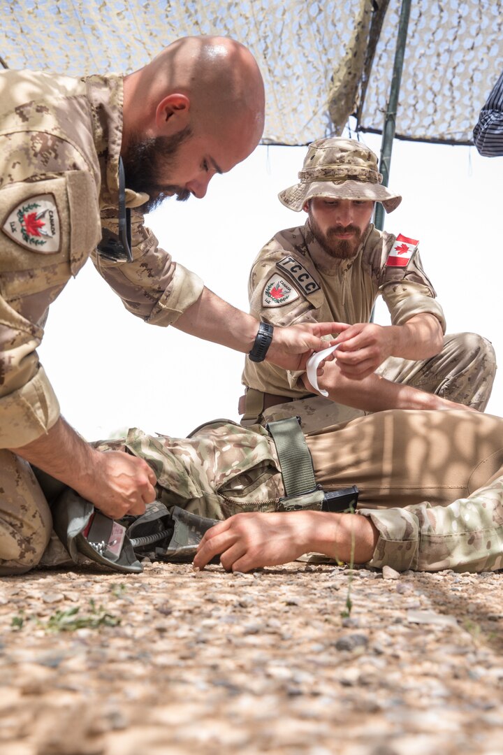 Canadian soldiers Master Cpl. Marc Deschesnes, left, and Cpl. Dave Lucas, assigned to the Qayyarah West Canadian Training Team, demonstrate the proper procedure for treating a chest wound to Iraqi provincial police members on Qayyarah West Airfield, Iraq, May 19, 2019. Iraqi students go through a four-week Wide Area Security Forces class taught by Canadian soldiers to learn essential combat skills like first aid, tactical movement, urban operations, and detainee procedures to enhance the Iraqi Security Forces’ combat skills and self-sufficiency. Coalition Forces are in Iraq at the invitation of the Government of Iraq to train and advise in support of the enduring mission to defeat Daesh. (U.S. Army Reserve photo by Spc. DeAndre Pierce)