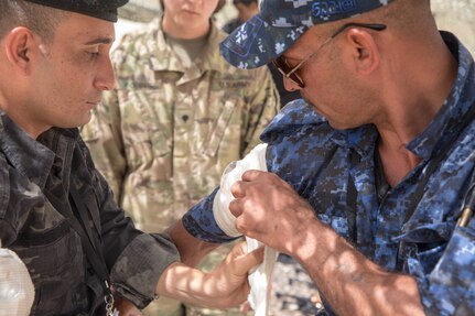 Iraqi provincial police members assigned to the 4th Ninawa Emergency Response Battalion apply a bandage during a combat first aid class on Qayyarah West Airfield, Iraq, May 19, 2019. Iraqi students go through a four-week Wide Area Security Forces class taught by Canadian soldiers to learn essential combat skills like first aid, tactical movement, urban operations, and detainee procedures to enhance the Iraqi Security Forces’ combat skills and self-sufficiency. Coalition Forces are in Iraq at the invitation of the Government of Iraq to train and advise in support of the enduring mission to defeat Daesh. (U.S. Army Reserve photo by Spc. DeAndre Pierce)