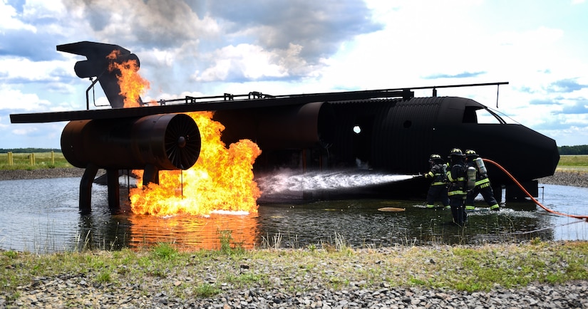 Fire fighters with the 87th Civil Engineer Squadron fire department work together to put out a fire during fire training on Joint Base McGuire-Dix-Lakehurst, New Jersey, June 3, 2019. The model aircraft fire is controlled by underground gas lines that can manipulate the size and intensity of the fire. (U.S. Air Force photo by Airman 1st Class Ariel Owings)