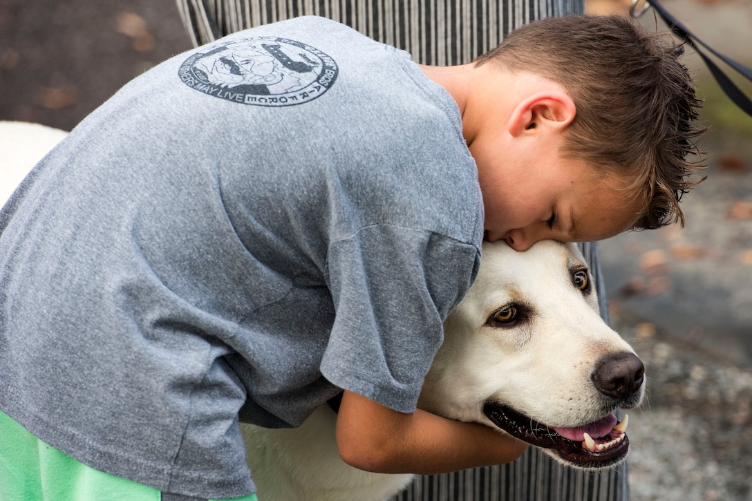 Remy, son of Tech. Sgt. Jared Stidham, 38th Rescue Squadron (RQS) pararescueman, hugs a dog while awaiting his father’s return during a redeployment, June 10, 2019, at Moody Air Force Base, Ga. Personnel from the 38th RQS deployed as part of Combined Joint Task Force-Horn of Africa where they provided robust personnel recovery capabilities to support the security objectives of United States Africa Command and United States European Command. (U.S. Air Force photo by Senior Airman Erick Requadt)
