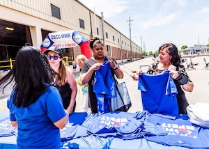 three women receive t-shirts from a table