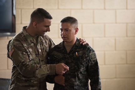 U.S. Army Sgt. Carlos Solver, Puerto Rico National Guard Security Forces Training (SFT) instructor, discusses graduation procedures with Honduran Army Commando 2 Edikson Barahona, 2nd Engineer Company general relations, during the SFT course June 8, 2019, at the 1st Artillery Battalion in Zambrano, Honduras. Honduran Army soldiers participated in the two-week SFT course led by U.S. Army Puerto Rico National Guard service members assigned to Task Force ¬¬– Borinqueneer. The course taught them about security techniques and procedures to include formation, breaching, weapons training, casualty care, vehicle searching and tactical control points. The training was hosted as way to strengthen the host nations counter threat ability. (U.S. Air Force photo by Staff Sgt. Eric Summers Jr.)