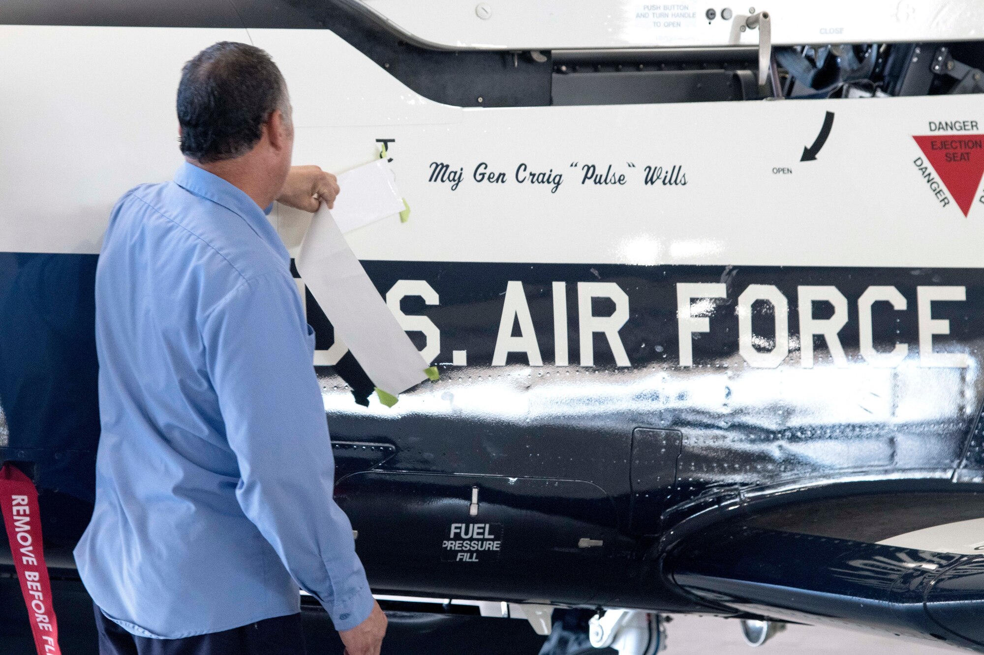 A member of the 12th Flying Training Wing unveils Maj. Gen. Craig Wills, 19th Air Force commander, name on the side of a T-6 Texan during the 19th Air Force change of command ceremony June 13, 2019, at Joint Base San Antonio-Randolph, Texas.  Wills comes to JBSA-Randolph from his previous assignment as the deputy chief of the Office of Security Cooperation-Iraq. (U.S. Air Force photo by Sean M. Worrell)