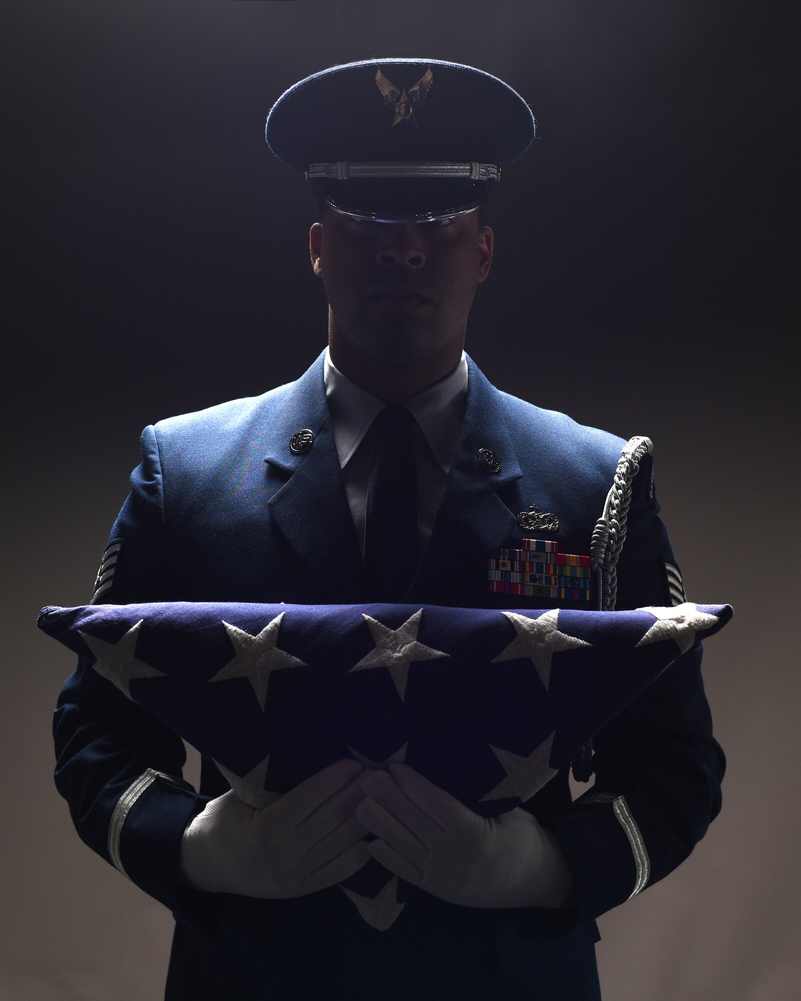Staff Sgt. Alonzo Clark, 319th Air Base Wing Honor Guard program manager, holds a folded flag of the United States of America to his chest June 5, 2019, on Grand Forks Air Force Base, North Dakota. Clark acted as program manager for two years, with prior experience in the 319th Security Forces Squadron. (U.S. Air Force photo illustration by Senior Airman Elora J. Martinez)