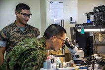 U.S. Marine Corps Staff Sgt. Joshua Coffill, left, shows Japanese Ground Self-Defense Force Sgt. Masaki Tetusuda, right, a broken motherboard through a microscope during a community exchange program tour on Camp Kinser, Okinawa, Japan June 7, 2019. During the tour, hosted by Combat Logistics Regiment 35, service members visited the base dining facility, supply management unit, a maintenance shop and the Battle of Okinawa historical display, before taking part in a social at the USO. The purpose of the program is to create bonds and increase operational understanding between the JGSDF and the U.S. Marine Corps. Coffill, a maintenance chief with CLR-35, 3rd Marine Logistics Group, is a native of San Diego, California. Tetusuda, is a native of Fukuoka, Japan.  (U.S. Marine Corps photo by Pfc. Courtney A. Robertson)