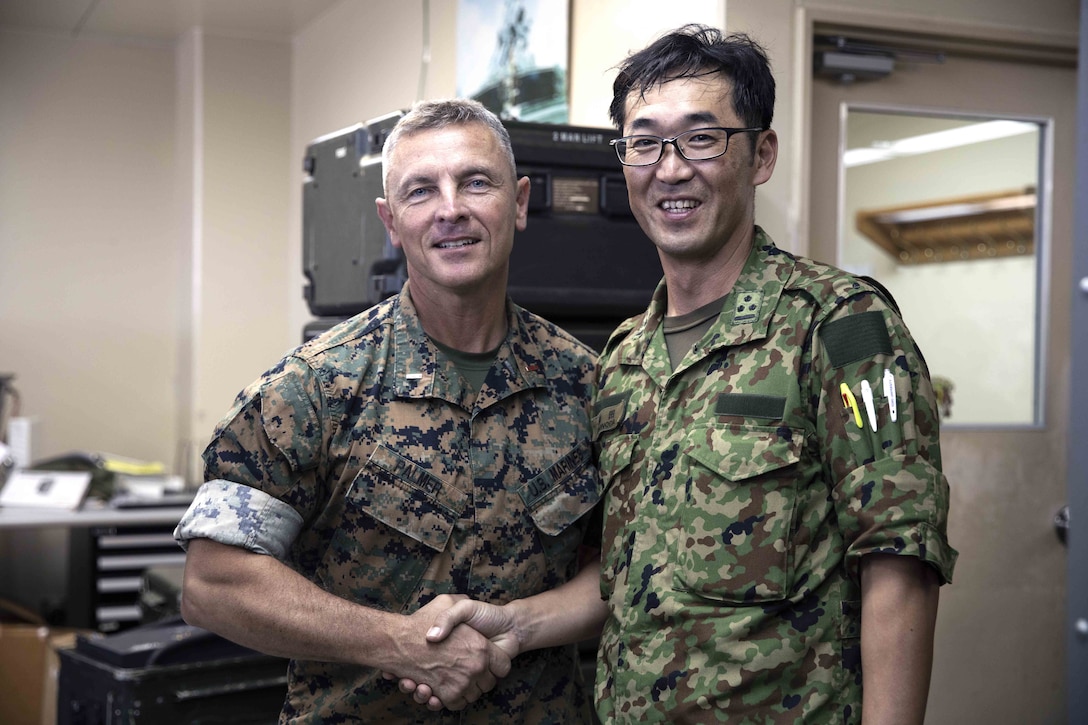 U.S. Marine Corps Chief Warrant Officer 4 Roderick Palmer shakes hands with Japanese Ground Self-Defense Force Capt. Yuki Sonoda during a community exchange program tour on Camp Kinser, Okinawa, Japan June 7, 2019. During the tour, hosted by Combat Logistics Regiment 35, service members visited the base dining facility, supply management unit, a maintenance shop and the Battle of Okinawa historical display, before taking part in a social at the USO. The purpose of the program is to create bonds and increase operational understanding between the JGSDF and the U.S. Marine Corps. Palmer, the company commander of Maintenance Company, CLR-35, 3rd Marine Logistics Group, is a native of Tallahassee, Florida. Sonoda is a native of Fukuoka, Japan.  (U.S. Marine Corps photo by Pfc. Courtney A. Robertson)