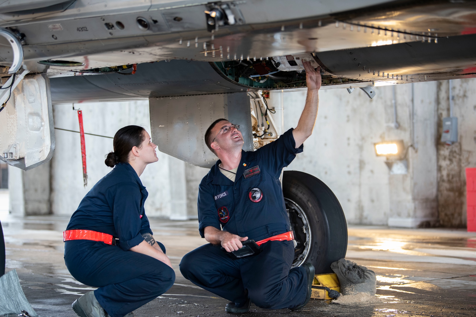 U.S. Air Force Staff Sgt. Brandon Deem, a dedicated crew chief assigned to the 67th Aircraft Maintenance Unit, inspects an F-15 Eagle while teaching an Airman at Kadena Air Base, Japan, June 11, 2019.
