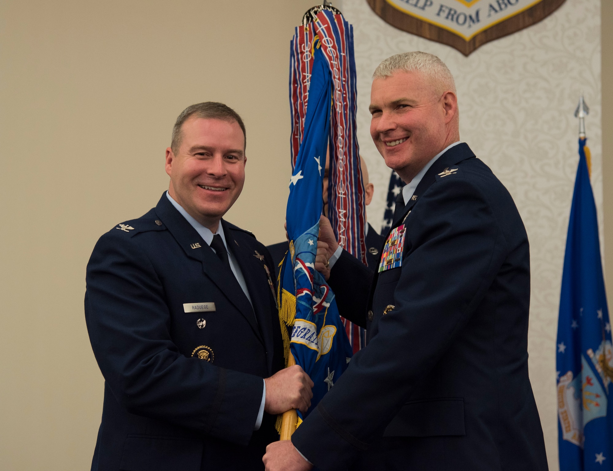 Colonel Chad D. Raduege, Director of Cyberspace and Information Dominance, presents the Air Force Network Integration Center guidon to Colonel Marc L. Packler during a change of command ceremony June 13 at Scott Air Force Base, Ill. Colonel Packler arrived from Scott Air Force Base, Ill, where he served as the 375 Communications Group Commander.