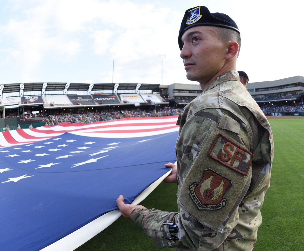 A member of the 72nd Security Forces Squadron helps hold a giant American flag in place during the opening ceremonies of an Oklahoma City Dodgers minor league baseball game during Military Appreciation Night May 17, 2019, Oklahoma City, Oklahoma. Proper display, handling and disposal of the flag is part of etiquette taught to military members throughout their careers. (U.S. Air Force photo/Greg L. Davis)
