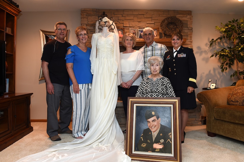 The family of Aida Bonsonto pauses for a photo with Brig. Gen. Kris A. Belanger, Commanding General, 85th U.S. Army Reserve Support Command and a wedding dress made from a World War II parachute that her husband sent home.