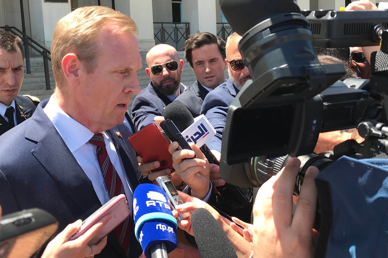 Man surrounded by reporters.