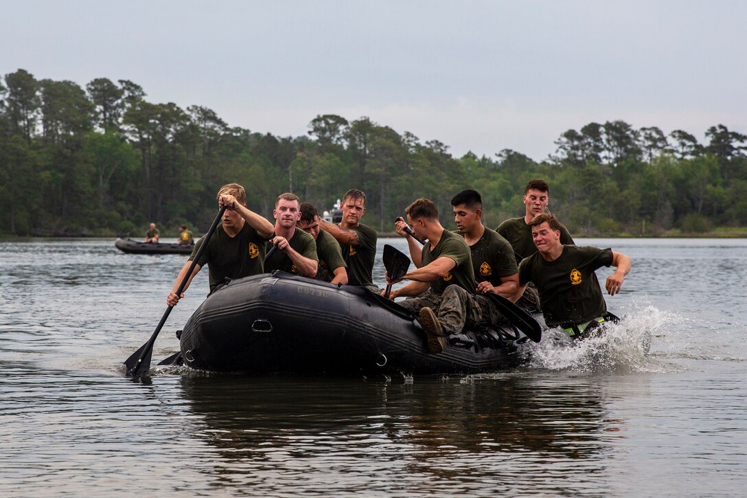 A group of Marines row a craft on water.