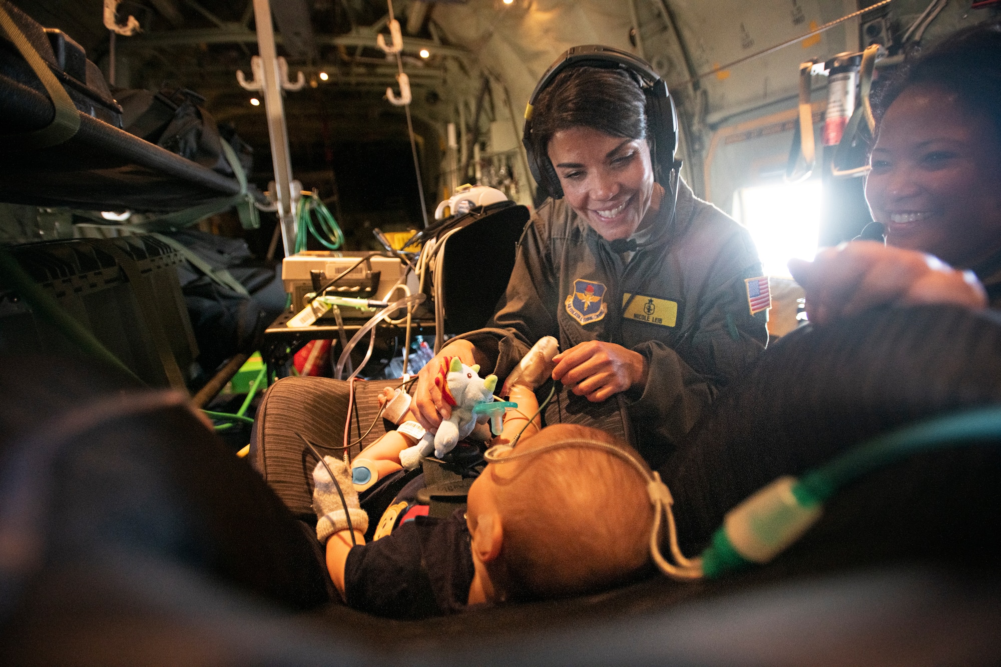 U.S. Air Force Capt. Nicole Leib and Maj. Mariana Lacuzong, 59th Medical Wing Critical Care Air Transport Team nurses, play with 7-month-old patient, Nakoa Crawford, during the five-hour flight from Dallas to San Diego, June 7, 2019. (U.S. Air Force photo by Tech. Sgt. Katherine Spessa)