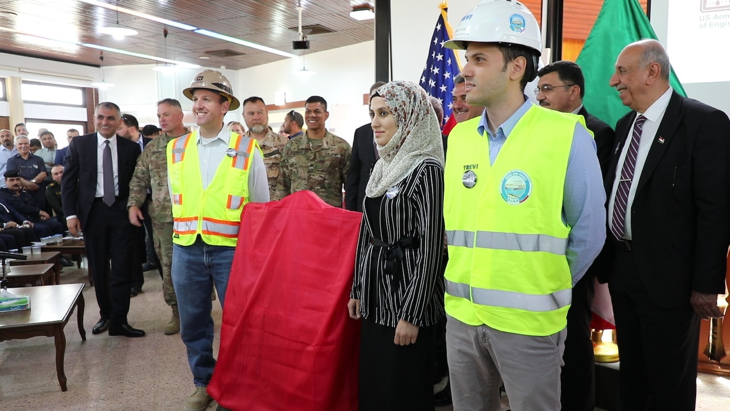 Workers from the U.S. Army Corps of Engineers, the Iraqi Ministry of Water Resources and Italian Company Trevi S.p.A. stand ready to unveil a new plaque that will hang at Mosul Dam, commemorating the 3-year partnership between the three countries of Iraq, the U.S. and Italy. The plaque was unveiled during a ceremony on June 15, 2019, at the Mosul Dam in Iraq. The Mosul Dam Project started in 2016 as a joint project among the Iraq Ministry of Water Resources, the U.S. Army Corps of Engineers, and Trevi in an effort to stabilize and repair the infrastructure of Mosul Dam. The dam, which is the largest in Iraq, and the fourth largest in the Middle East, supplies water, hydropower, irrigation and flood control to the region.
