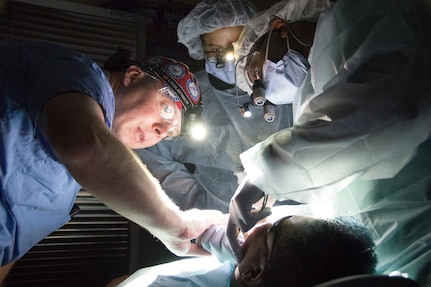 Navy Reserve Lt. Cmdr. Andrew Tellington, left, a dentist with the Operational Health Support Unit, Bremerton; Air National Guard Tech. Sgt. Ashley Craig, center, the dental noncommissioned officer in charge and a dental technician with the 175th Medical Group, Baltimore, and Air Force Capt. Aaron Gause, a dentist resident at Joint Base Andrews, Maryland, complete a dental procedure after a power outage stripped the facility of electricity. The lack of power introduced a new obstacle for service members to overcome while training in a real world scenario.