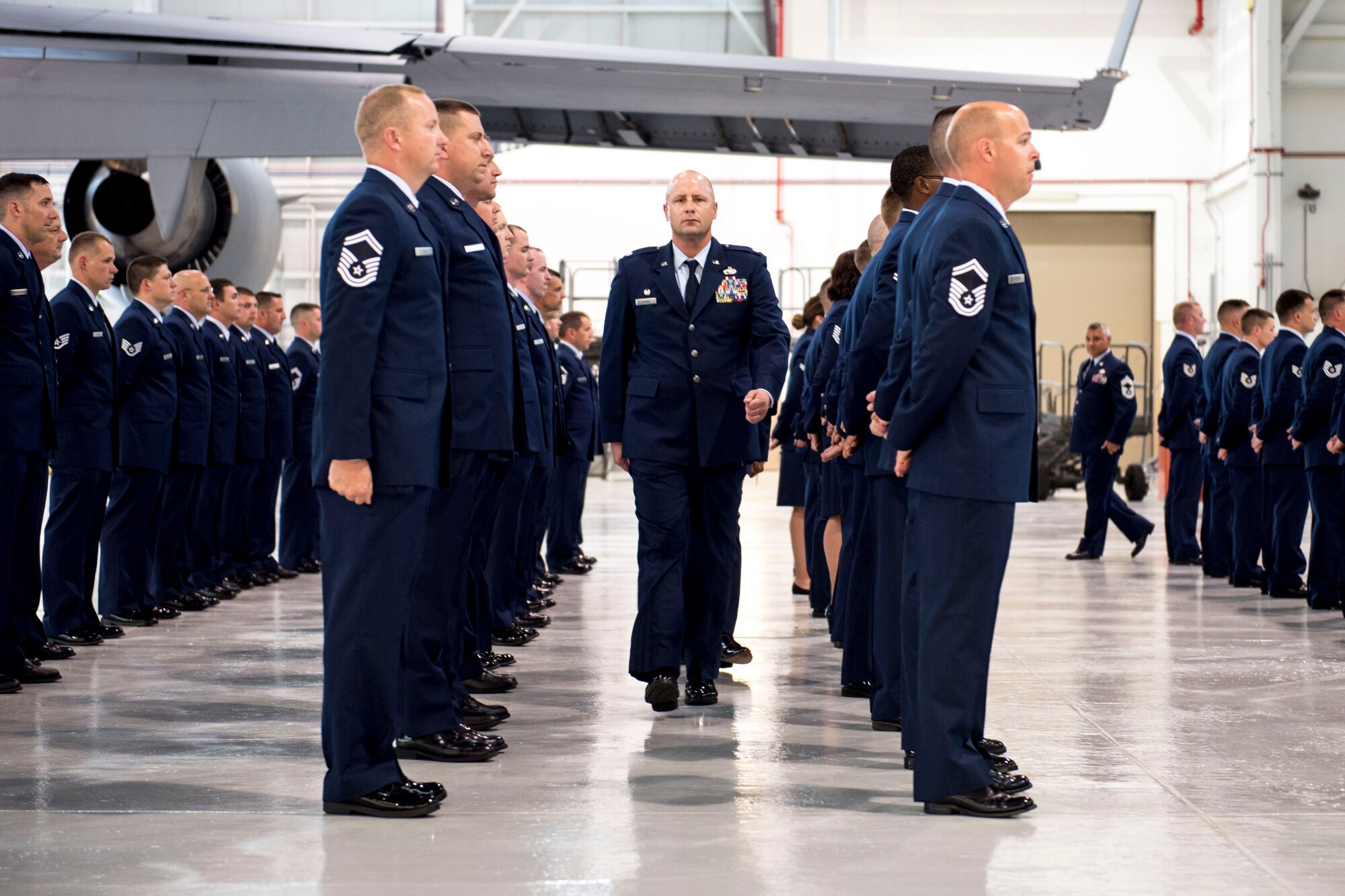 Lt. Col. Jason L. Harris, the167th Aircraft Maintenance Squadron Commander, walks between Airmen during an open ranks blues inspection in an aircraft hangar, June 6, 2019. During the inspection, ribbons, stripes and accouterments were checked to ensure all Airmen are meeting Air Force uniform standards.  (U.S. Air National Guard photo by Tech. Sgt. Jodie Witmer)