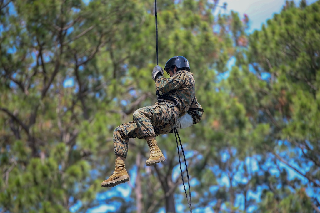 A Marine Corps recruit rappels down from a tower.