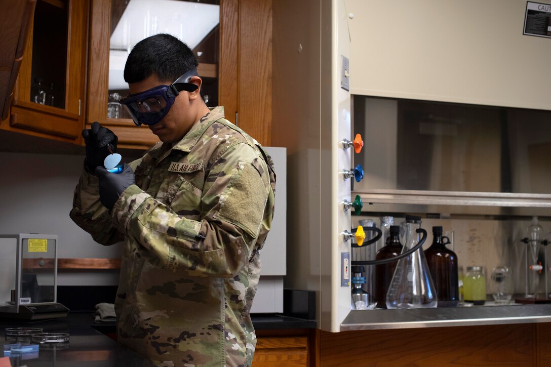 Airman 1st Class John Sanchez, 319th Logistics Readiness Squadron fuels lab technician, prepares a membrane filter to be dries June 12, 2019, on Grand Forks Air Force Base, North Dakota. The filter is baked dry before being used to test the weight of fuel, which must be confirmed clean and water-free prior to use in an aircraft. (U.S. Air Force photo by Senior Airman Elora J. Martinez)