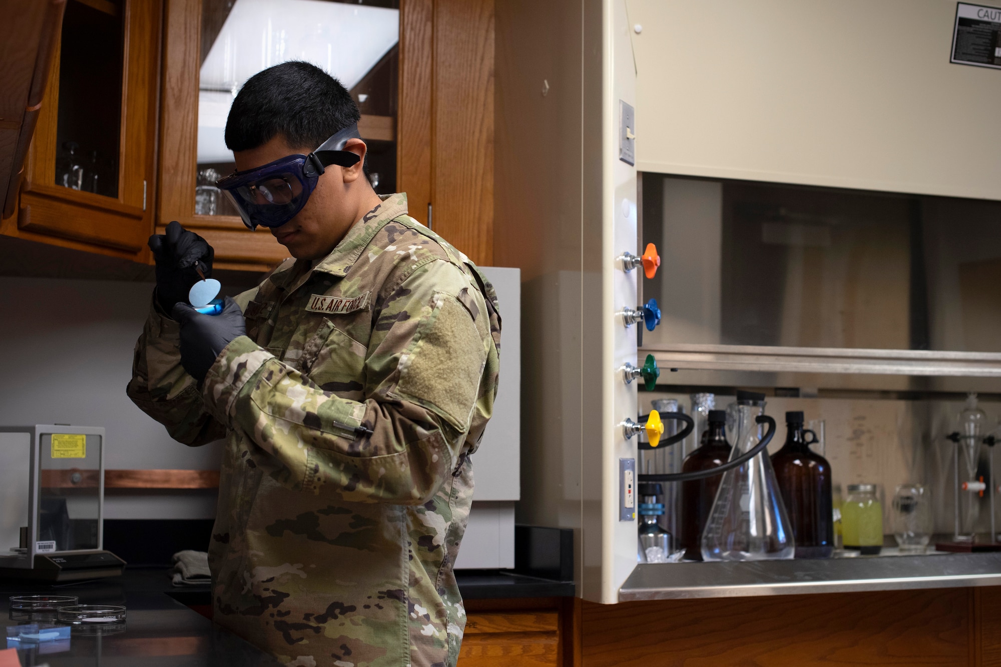 Airman 1st Class John Sanchez, 319th Logistics Readiness Squadron fuels lab technician, prepares a membrane filter to be dries June 12, 2019, on Grand Forks Air Force Base, North Dakota. The filter is baked dry before being used to test the weight of fuel, which must be confirmed clean and water-free prior to use in an aircraft. (U.S. Air Force photo by Senior Airman Elora J. Martinez)