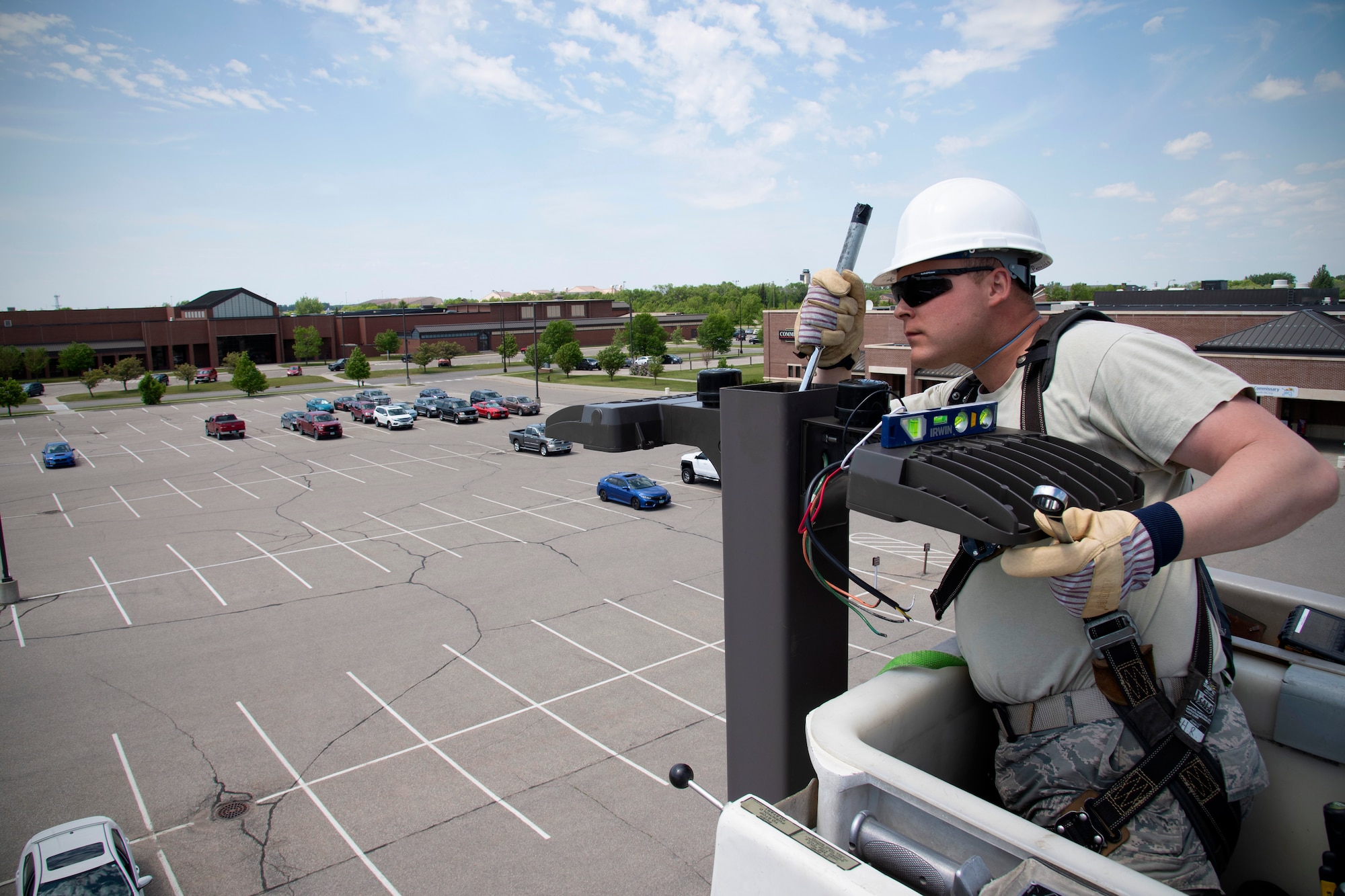 Airman 1st Class David Peranich, 319th Civil Engineer Squadron electrical systems journeyman, installs new streetlights in the commissary parking lot June 12, 2019, on Grand Forks Air Force Base, North Dakota. Peranich and other electrical systems airmen began replacing all base streetlights with brighter, more energy-efficient LED bulbs as soon as weather allowed, and are scheduled to complete their project at the end of summer. (U.S. Air Force photo by Senior Airman Elora J. Martinez)