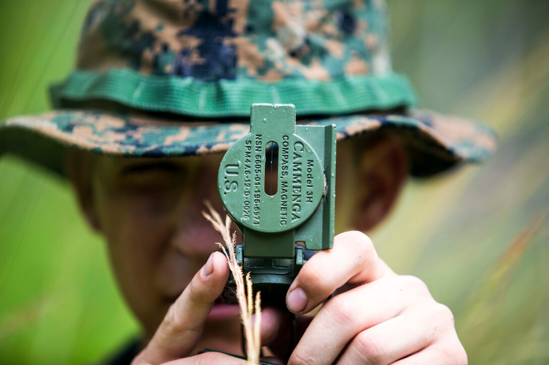 A Marine recruit looks through a compass.